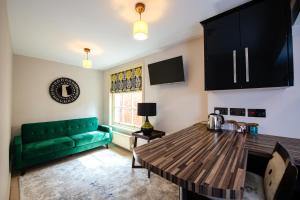 ein Wohnzimmer mit einem grünen Sofa und einem Tisch in der Unterkunft RHUBARB at Drapers Hall in Shrewsbury