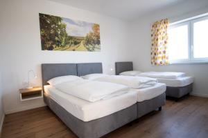 a bedroom with three beds and a painting on the wall at Family XL - Bungalows in Lutzmannsburg