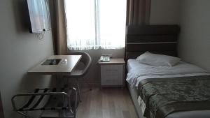 um pequeno quarto com uma cama, uma secretária e uma janela em BAL Mini Hotel em Tirebolu