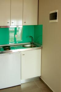 a kitchen with white cabinets and a sink at Emmeleia Accommodation by Maria Riga in Ouranoupoli