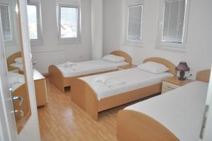 a room with two beds and a table and windows at Guest House Miranda in Ohrid