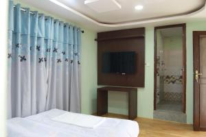 a bedroom with a bed and a tv and curtains at Kathway Hostel & Homestay in Kathmandu