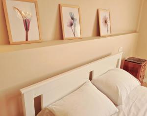 1 dormitorio con 1 cama blanca y 3 cuadros en la pared en Appartamento in Piazza Nova, en Pratovecchio