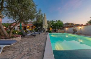 a swimming pool with lounge chairs and an umbrella at Villa Štrkalj ZadarVillas in Murvica
