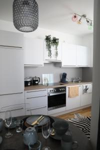 a kitchen with white cabinets and a table with wine glasses at City-Apartment Die kleine Mü in Gmunden
