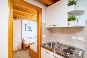 cocina con armarios blancos, fregadero y cama en Apartment Ribambit en Dubrovnik