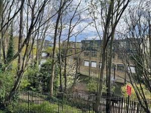 a view of a building with a fence and trees at Canal-Side Boutique Apartment in London