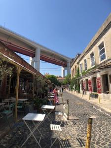 LX Lisboa Cozy studio في لشبونة: شارع فيه طاولات وكراسي وجسر