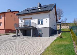 ein weißes Haus mit einem Balkon und einer Auffahrt in der Unterkunft Apartament Oliwkowy in Chmielno