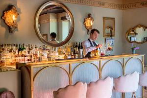 a man standing behind a bar with a mirror at Relais & Châteaux Il Falconiere in Cortona