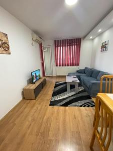 een woonkamer met een blauwe bank en een tv bij Apartman Kasija in Jagodina