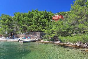 a red house on a hill next to a body of water at Candela, No 3 in Starigrad-Paklenica