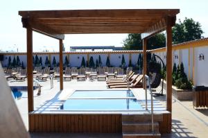a swimming pool with chairs and a pavilion at Motel Alaska in Deva