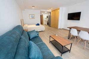 a living room with a blue couch and a bedroom at A&F Apartments in Nerja