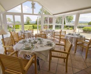 uma sala de jantar com mesas, cadeiras e janelas em Knoll Hill Farm, The Place To Stay em Frome