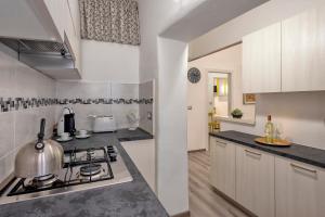 a kitchen with white cabinets and a stove top oven at MACHIN 57 - Magnolia Holidays in Alghero