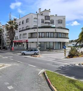 um carro estacionado em frente a um edifício branco em Condomínio Del Rey em Charneca