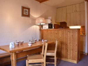 una cucina con tavolo in legno, 2 sedie e forno a microonde di Appartement Méribel, 2 pièces, 5 personnes - FR-1-180-94 a Méribel
