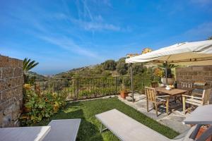 a patio with a table and chairs and an umbrella at Il Nido in Pompeiana