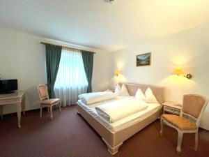カンポ・ディ・トレンスにあるホテル ラルチのベッド、デスク、椅子が備わるホテルルームです。