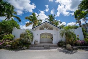 a white house with palm trees and a driveway at Family Dominicus Apartment - Bayahibe in Bayahibe