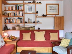 a living room with a red couch and bookshelves at Appartement 3 pièces avec balcon et WIFI à 150m des pistes, 6 personnes - Méribel - FR-1-180-155 in Méribel