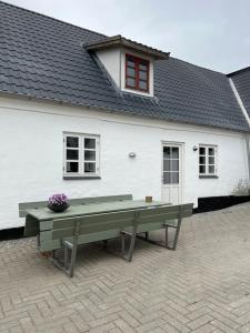 a white house with a bench in front of it at Søndervang, ferielejlighed in Svinninge