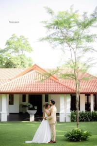 una sposa e uno sposo in piedi di fronte a una casa di Villa Crystals a Colombo