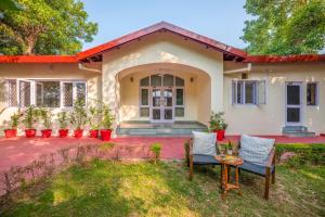 Una casa con dos sillas y una mesa en el patio. en Bamboo Grove by VEO - Part of StayVista, en Dehradun