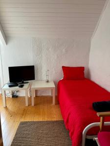 a bedroom with a red bed and a desk with a tv at Maison de charme entre terre et mer, proche plages in Névez