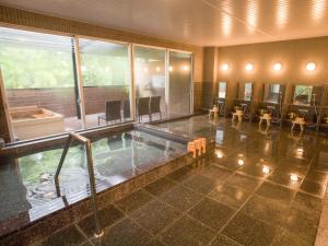 an indoor swimming pool in a building with tables and chairs at LiVEMAX RESORT Hakone Ashinoko in Hakone