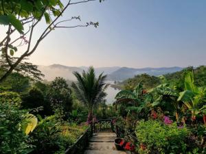 un chemin à travers un jardin avec des montagnes en arrière-plan dans l'établissement Baanhatsompaen homestay, à Ranong