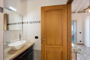 La salle de bains est pourvue d'un lavabo et d'une porte en bois. dans l'établissement Timo, à Pompeiana