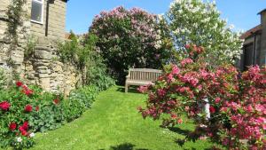 un banco sentado en medio de un jardín con flores en Pear Tree House B&B, en Pickering