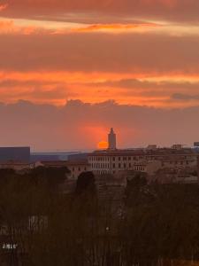 einen Sonnenuntergang über einer Stadt mit einem Gebäude und einem Leuchtturm in der Unterkunft Casina Tuareg in Livorno