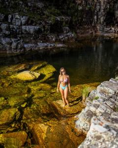 uma mulher de biquíni em cima de uma pedra na água em Camping do Tamanduá em Capitólio