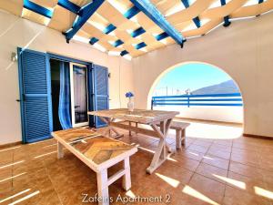 a table and benches in a room with a view of the ocean at Zafeiris Apartments in Livadia +28 photos