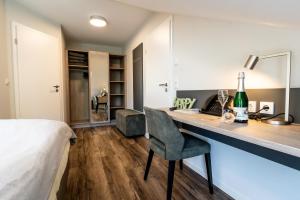 a bedroom with a bed and a desk with a bottle of wine at Hotel Landhaus Silbertanne in Rotenburg an der Fulda