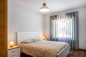 une chambre avec un lit et une grande fenêtre dans l'établissement Apartment Beach Waves Home, à Nazaré 17 autres photos