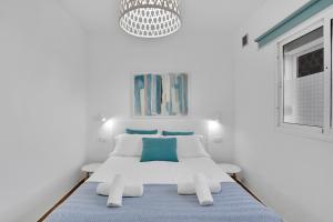 una camera da letto bianca con un letto e un lampadario di Apartamentos Marinera I y II a Cotillo