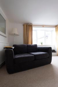 a black couch in a living room with a window at Character cottage in the heart of Uplyme. in Uplyme