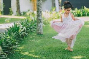a little girl in a pink dress dancing on the grass at Villa Crystals in Colombo