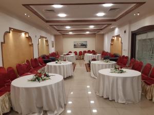 a conference room with tables and red chairs at Amman Ambiance Hotel  in Amman
