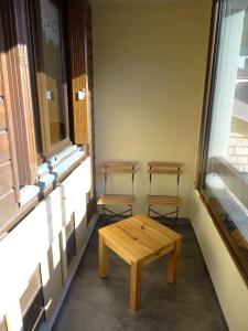 dwie ławki i stół w pokoju z oknem w obiekcie Appartement au cœur du village avec parking privé w mieście Mijoux
