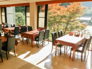 a restaurant with tables and chairs and a large window at LiVEMAX RESORT Okudogo in Matsuyama