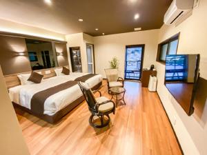 a bedroom with a bed and two chairs and a flat screen tv at LiVEMAX RESORT Okudogo in Matsuyama