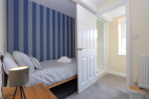 a bedroom with a bed with a blue striped wall at The Little Lion Inn, Red Lion in Wellingore