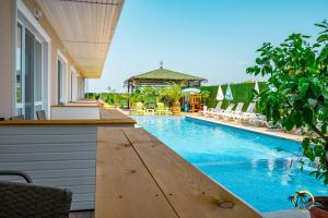 an outdoor swimming pool with a wooden table and chairs at Gradina Holiday in Sozopol