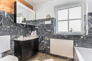 ein Bad mit einem Waschbecken, einer Badewanne und einem Fenster in der Unterkunft Gasthof Andrelwirt Rauris in Rauris