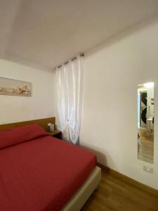 Un dormitorio con una cama roja y una ventana. en Cà dei Pòi - loft Stella Marina, en Riomaggiore